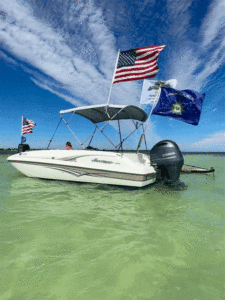 Boat with colorful flags flying against a backdrop of the ocean and a clear blue sky, representing the ultimate boat charter experience in Islamorada with Island Adventures.
